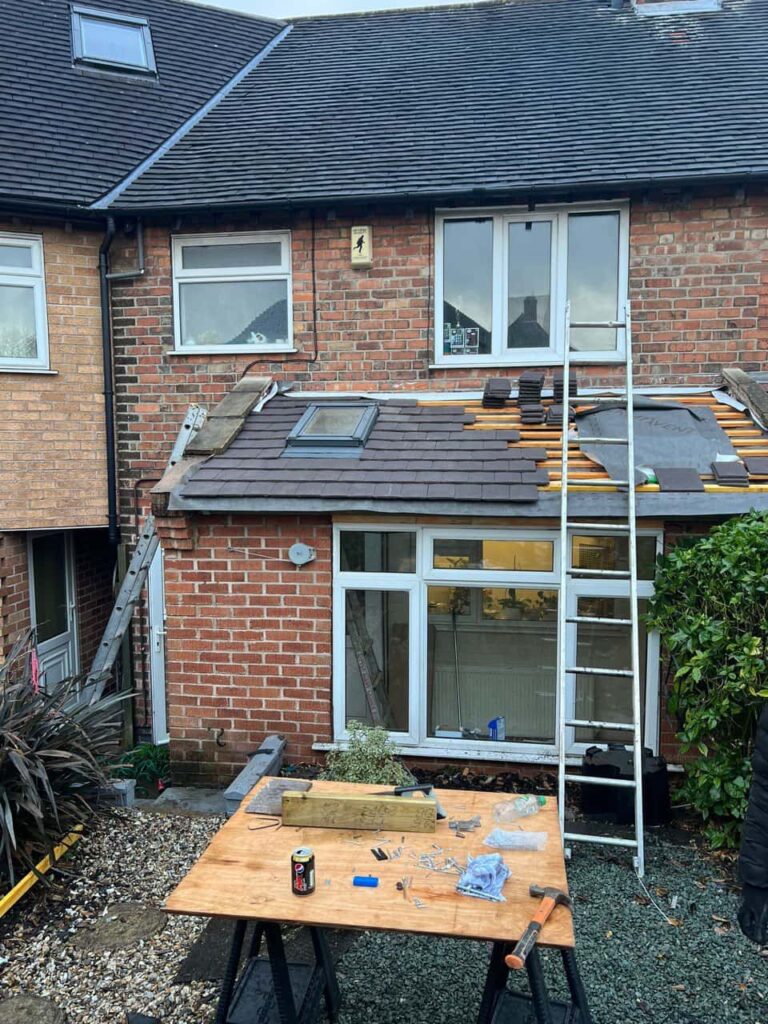 This is a photo of a roof extension that is having new roof tiles installed. This is a photo taken from the roof ridge looking down a tiled pitched roof on to a flat roof. Works carried out by Atherstone Roofing Repairs