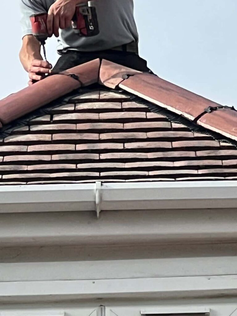 This is a photo of one of the operatives of Atherstone Roofing Repairs installing new ridge tiles